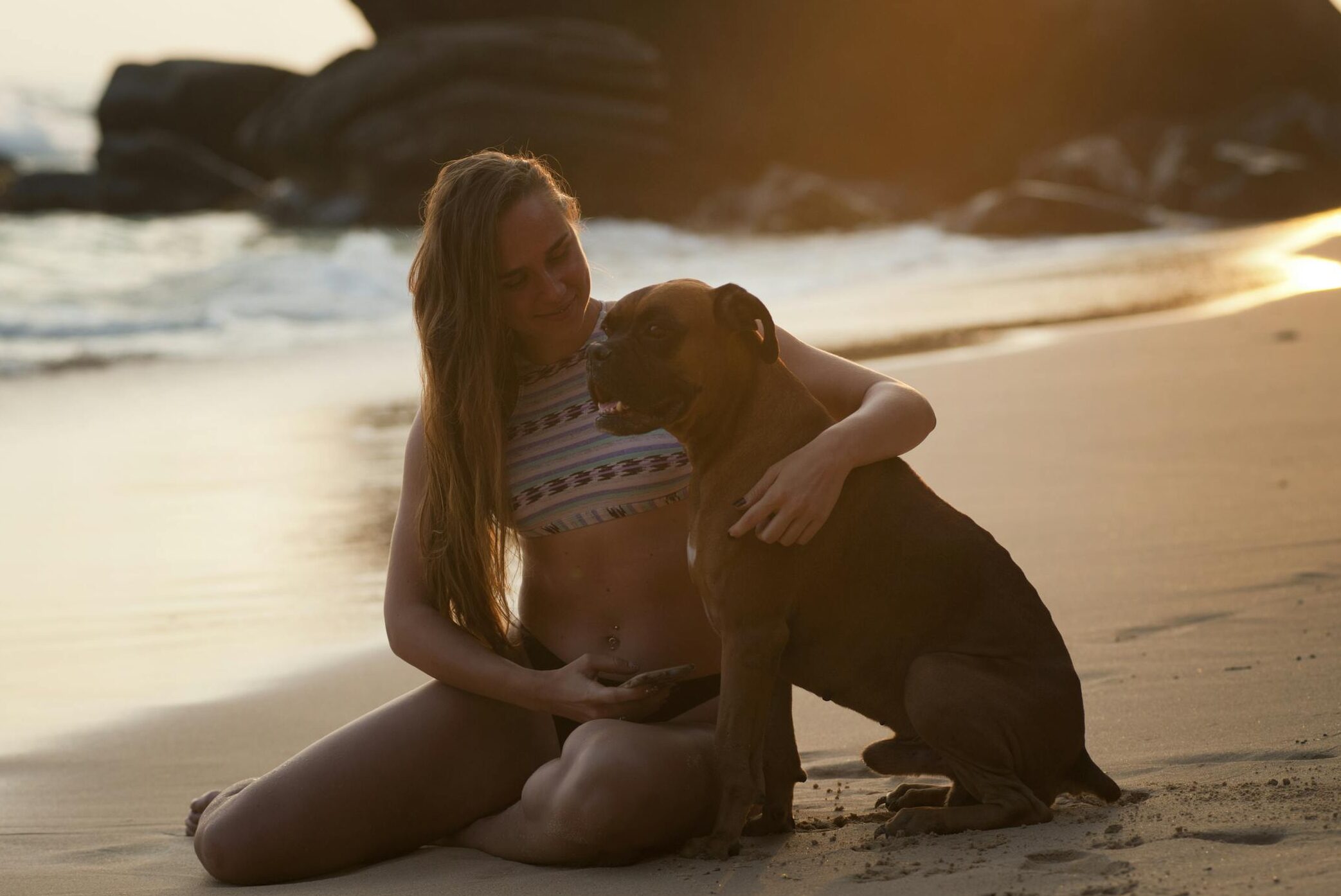 A woman and her dog enjoying a warm sunset together on Unawatuna Beach, Sri Lanka.