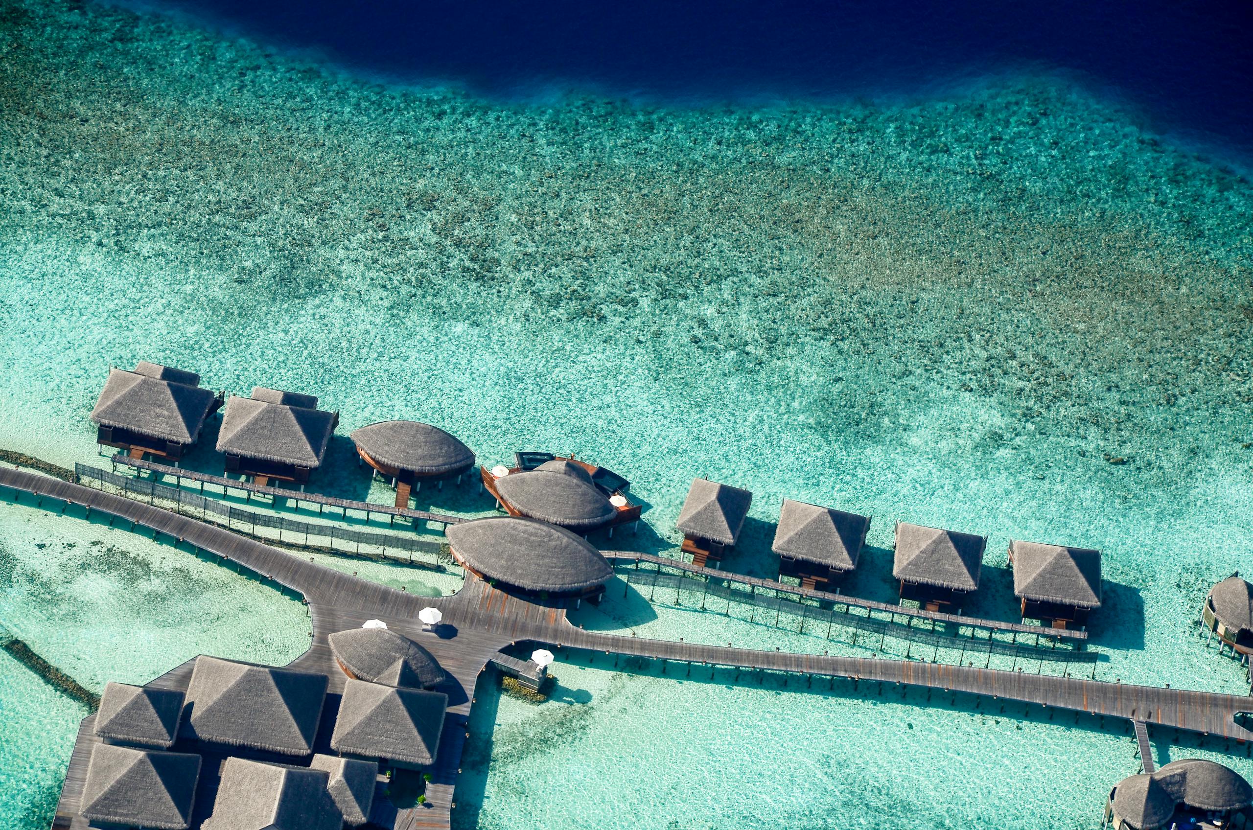 Stunning aerial shot of luxurious overwater villas in the Maldives, showcasing crystal clear turquoise waters.